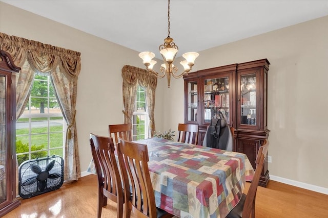 dining room with light wood finished floors, plenty of natural light, a notable chandelier, and baseboards