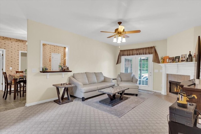 living area with a fireplace, a ceiling fan, and baseboards