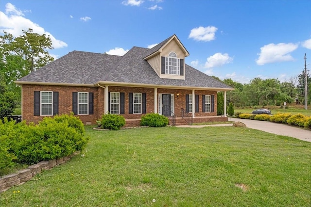 view of front of home with brick siding, a porch, and a front lawn