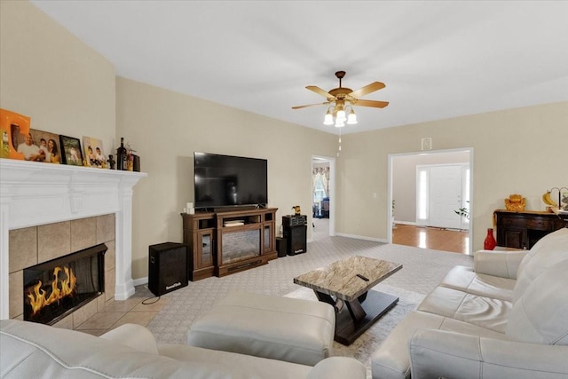 living room featuring ceiling fan, baseboards, light colored carpet, and a fireplace