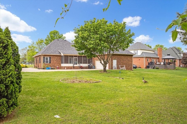 rear view of house with a lawn, a gazebo, a sunroom, and brick siding