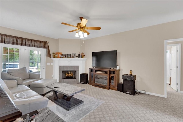 living room featuring a fireplace, ceiling fan, baseboards, and carpet floors