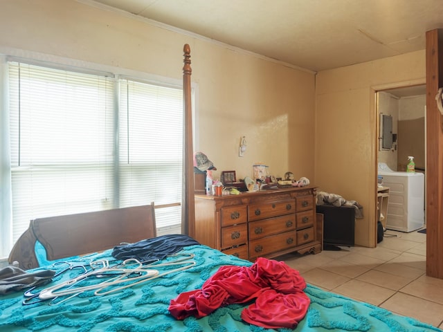 bedroom featuring multiple windows, crown molding, light tile patterned floors, and washer / dryer