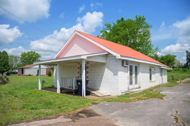 view of front of home with a wall mounted AC, a front lawn, concrete block siding, and metal roof
