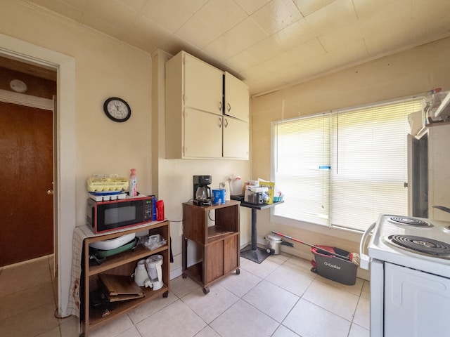 kitchen with light tile patterned flooring, black microwave, white electric range, and white cabinets