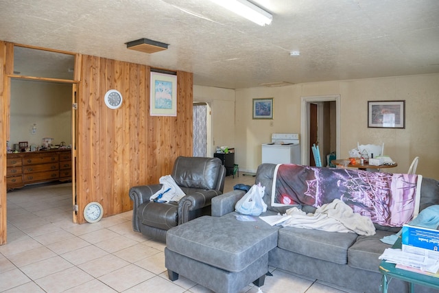 living area with light tile patterned flooring, wooden walls, and washer / clothes dryer