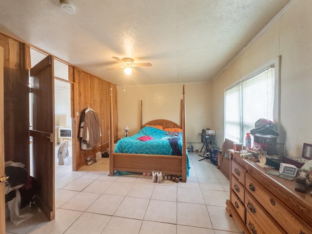 bedroom with wood walls, a ceiling fan, light tile patterned floors, crown molding, and a textured ceiling