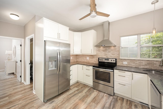 kitchen with appliances with stainless steel finishes, wall chimney range hood, a sink, decorative backsplash, and ceiling fan