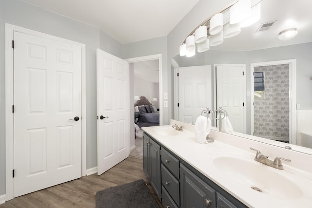 ensuite bathroom with wood finished floors, double vanity, and a shower