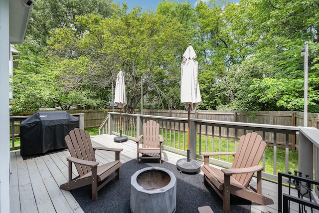 deck with a fire pit, a fenced backyard, and area for grilling