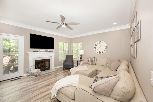living area with ceiling fan, wood finished floors, crown molding, a fireplace with flush hearth, and baseboards