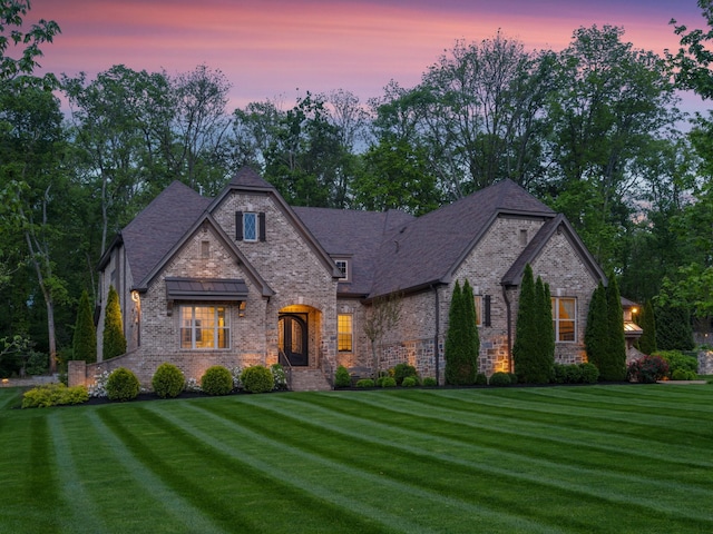 view of front facade featuring a lawn, stone siding, and brick siding