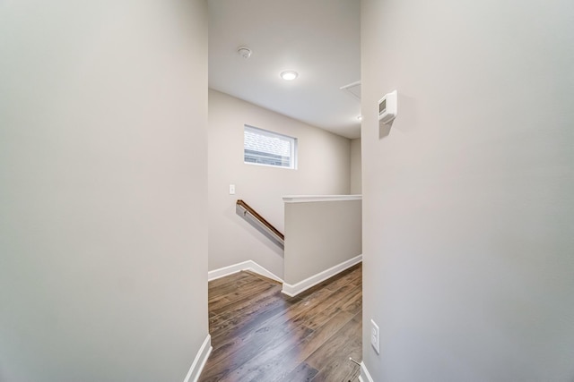 corridor with wood finished floors, baseboards, and an upstairs landing