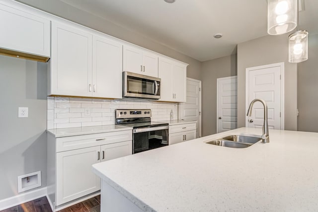 kitchen with white cabinets, stainless steel appliances, a sink, baseboards, and backsplash
