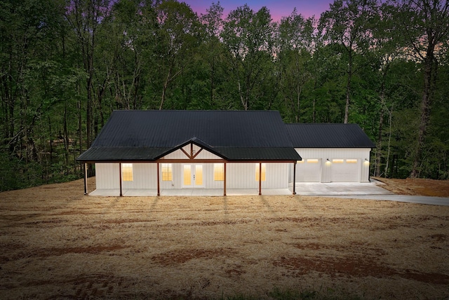 4151 Southside Rd, Southside, TN 37171 - garage at dusk featuring a forest view, french doors, and concrete driveway