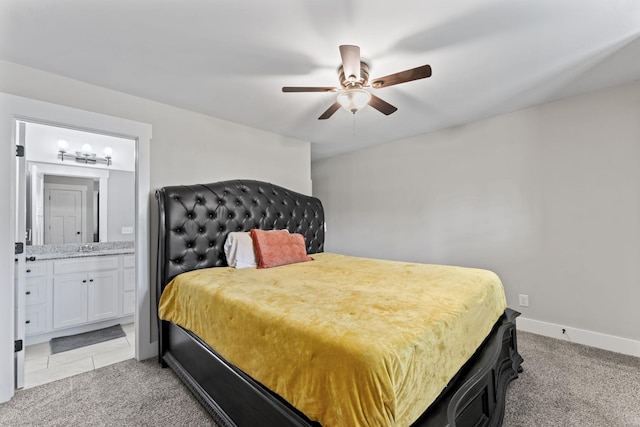 bedroom with baseboards, ceiling fan, ensuite bath, and light colored carpet