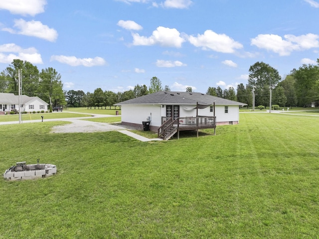 back of property with an outdoor fire pit, a wooden deck, stairway, a yard, and gravel driveway