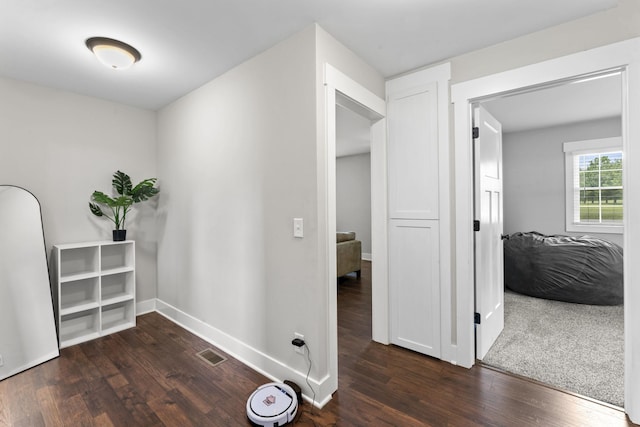 corridor with baseboards, visible vents, and wood finished floors