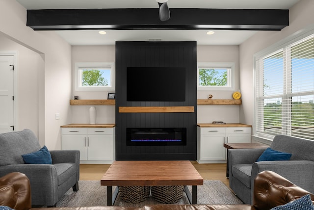 living room featuring light wood-type flooring, beam ceiling, and a healthy amount of sunlight