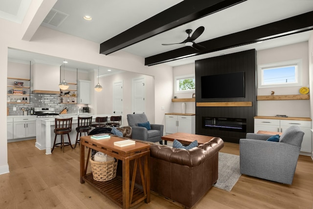 living room featuring beamed ceiling, light wood-style floors, visible vents, and ceiling fan