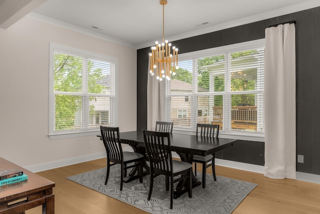 dining room featuring a chandelier, wood finished floors, visible vents, and ornamental molding