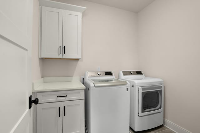 laundry room with cabinet space, baseboards, and washer and clothes dryer