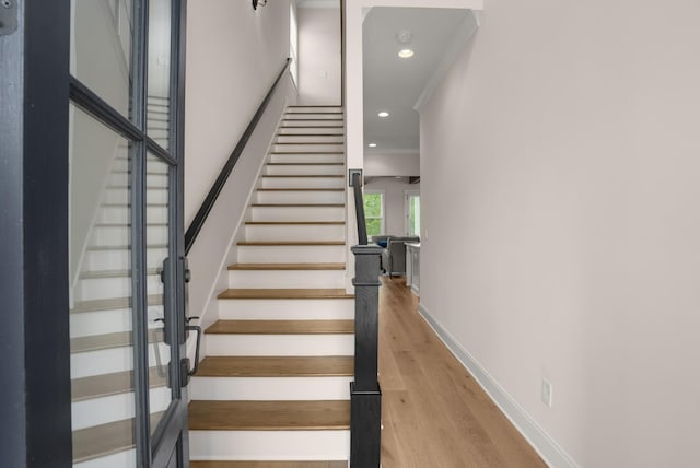 staircase featuring baseboards, wood finished floors, and recessed lighting