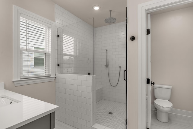 bathroom with a shower stall, toilet, vanity, baseboards, and recessed lighting