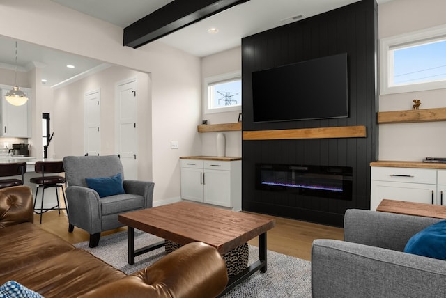 living room featuring a fireplace, recessed lighting, beamed ceiling, and light wood-style flooring