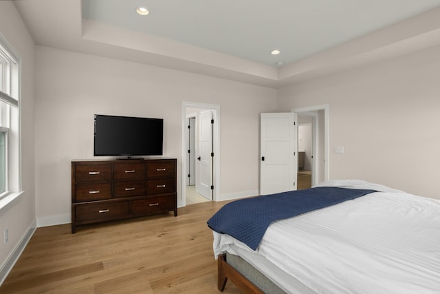 bedroom with baseboards, a tray ceiling, recessed lighting, and light wood-style floors