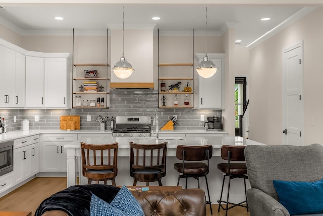kitchen featuring open shelves, light countertops, a breakfast bar area, and stainless steel appliances