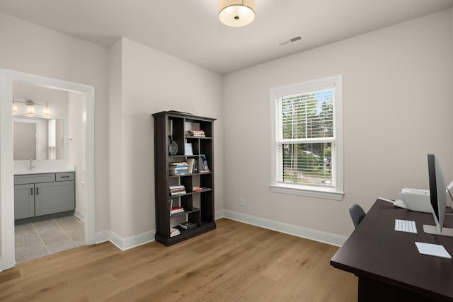 office area featuring light wood-style floors, visible vents, baseboards, and a sink