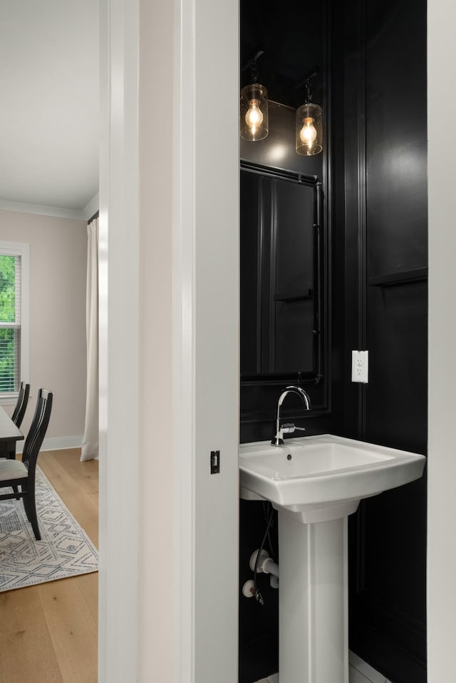 bathroom featuring wood finished floors, crown molding, and baseboards