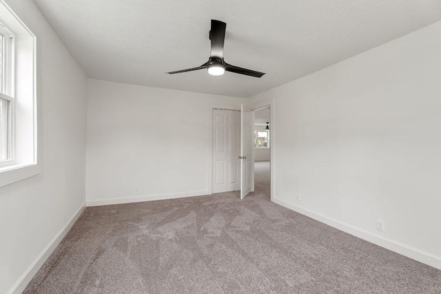 unfurnished bedroom featuring baseboards, carpet, a closet, and ceiling fan