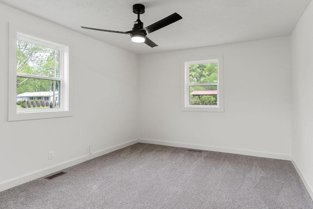 empty room with plenty of natural light, a ceiling fan, visible vents, and carpet flooring