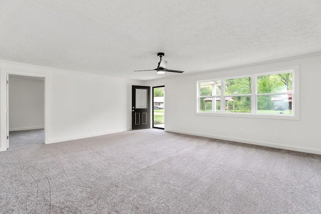 empty room featuring carpet, a textured ceiling, baseboards, and ceiling fan