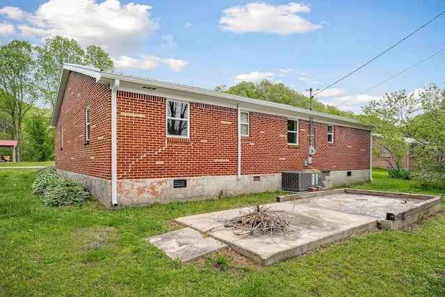rear view of property featuring a yard, cooling unit, crawl space, a patio area, and brick siding