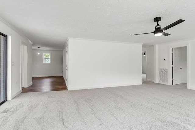 unfurnished living room with visible vents, ornamental molding, a textured ceiling, carpet flooring, and ceiling fan