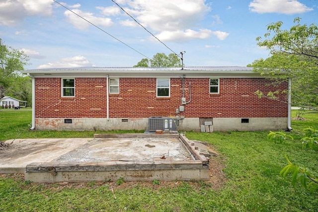 rear view of property with crawl space, central air condition unit, a lawn, metal roof, and brick siding