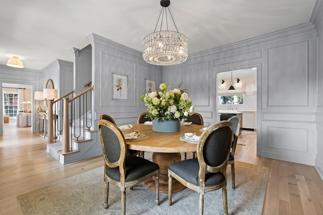 2931 Longford Dr, Murfreesboro, TN 37129 - dining space featuring stairway, an inviting chandelier, ornamental molding, light wood-style floors, and a decorative wall