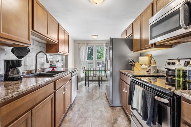 1646 S Jordan Dr, Clarksville, TN 37042 - kitchen with appliances with stainless steel finishes, a sink, brown cabinets, decorative backsplash, and dark stone countertops