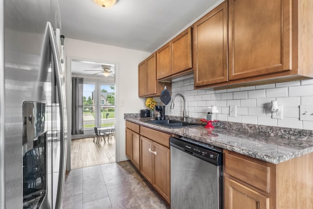 1646 S Jordan Dr, Clarksville, TN 37042 - kitchen featuring stainless steel appliances, a sink, decorative backsplash, ceiling fan, and brown cabinetry