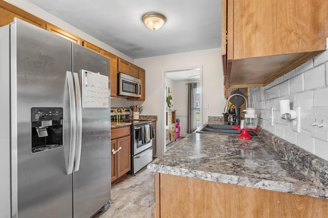 1646 S Jordan Dr, Clarksville, TN 37042 - kitchen featuring stainless steel appliances, brown cabinetry, tasteful backsplash, a sink, and dark countertops