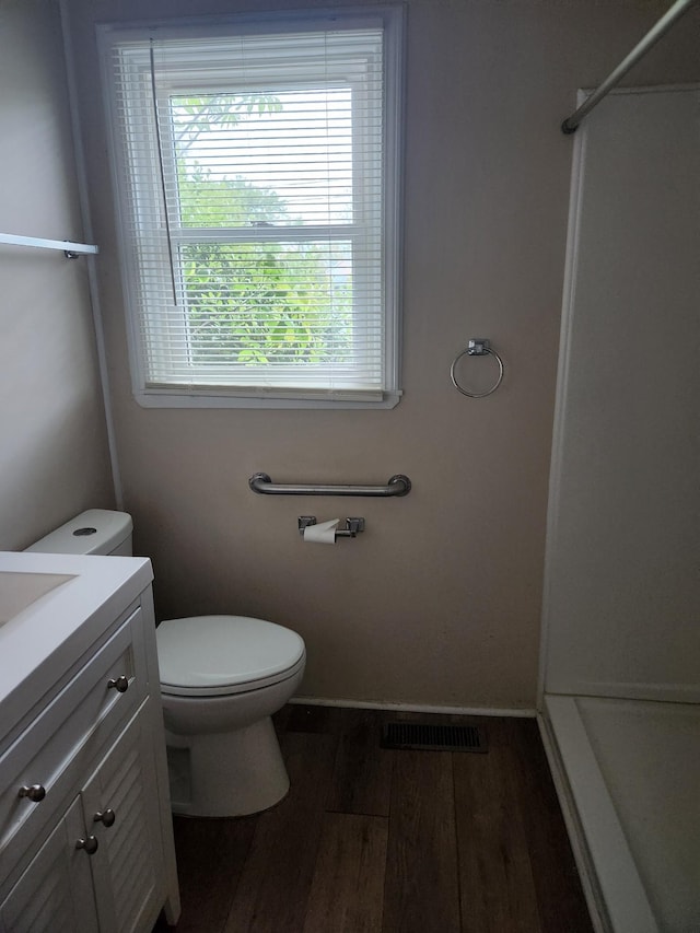 full bathroom with wood finished floors, vanity, a shower, toilet, and visible vents