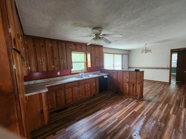 kitchen with a peninsula, a sink, a textured ceiling, dark wood finished floors, and ceiling fan with notable chandelier
