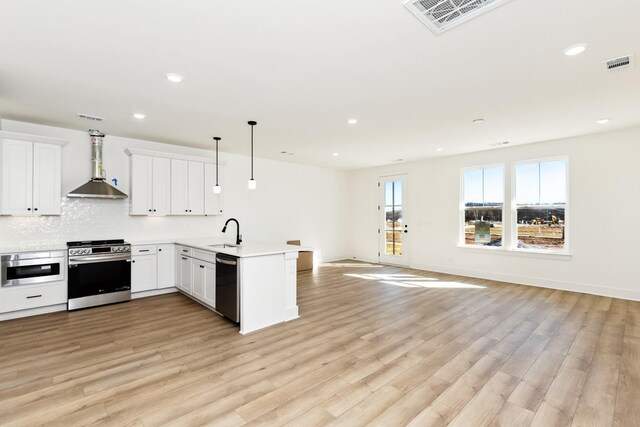 kitchen with stainless steel appliances, extractor fan, visible vents, a sink, and a peninsula
