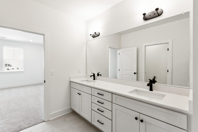bathroom with tile patterned floors, baseboards, a sink, and double vanity
