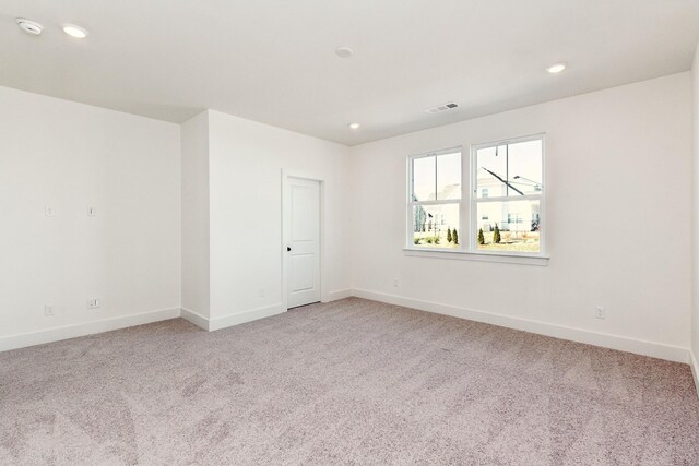spare room with light carpet and baseboards