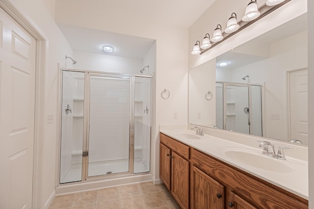full bath featuring double vanity, a shower stall, tile patterned flooring, and a sink