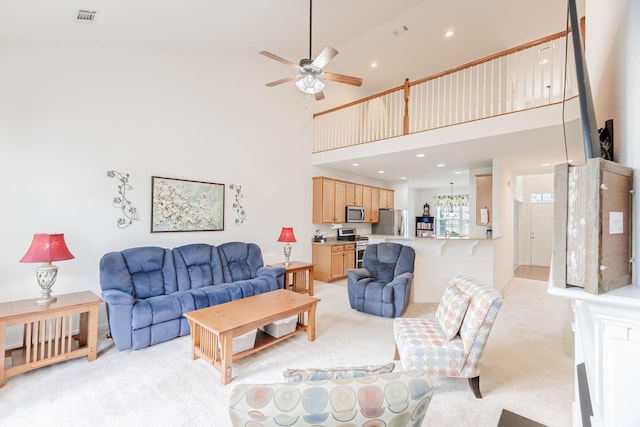 living area with a towering ceiling, visible vents, recessed lighting, light colored carpet, and a ceiling fan
